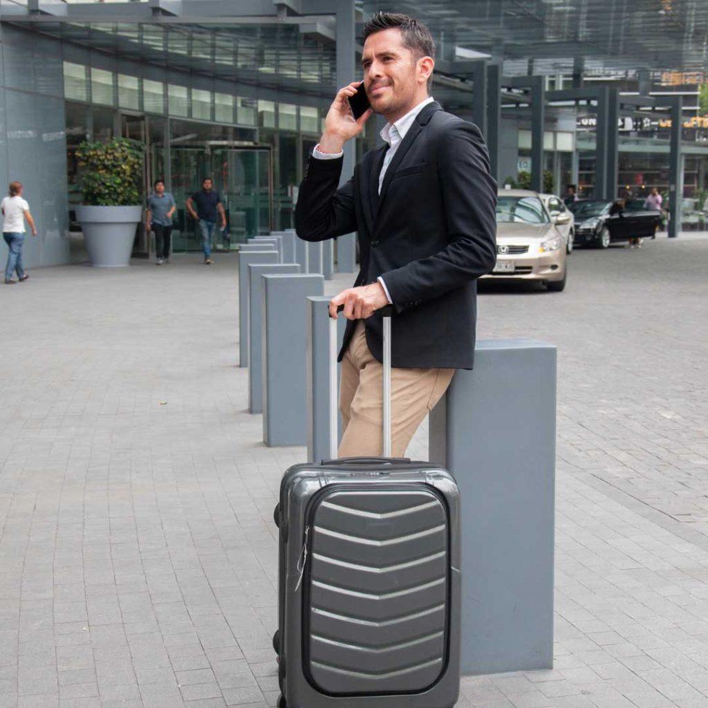 man in suit on cell phone standing with suitcase in hand