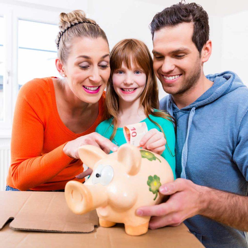 a man and a woman holding a piggy bank with a girl between them inserting a note