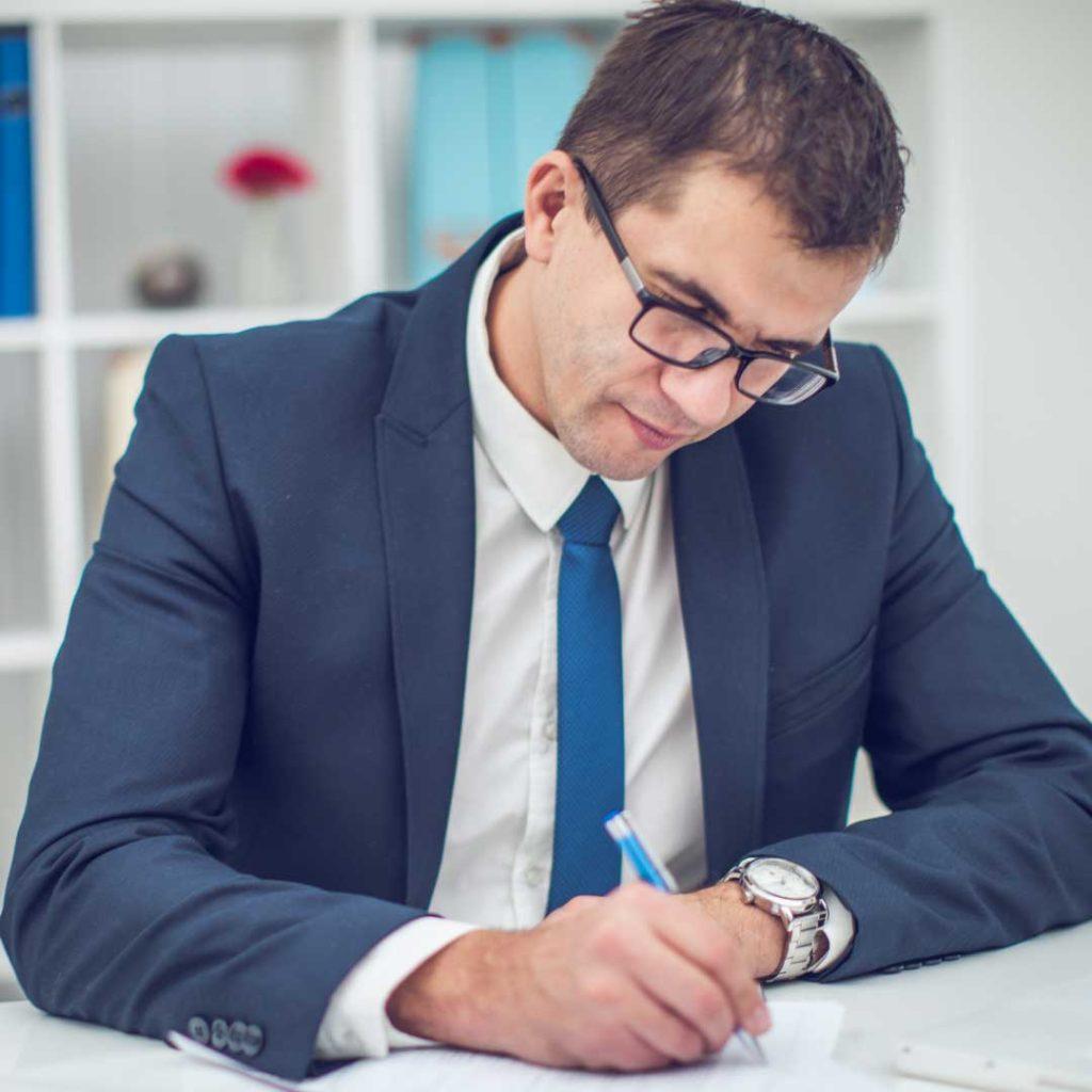 man wearing suit and eyeglasses writing