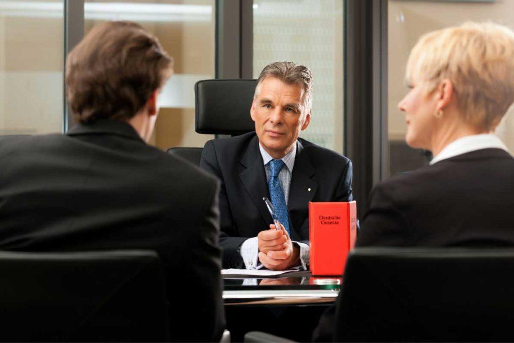 three people in a conference room talking to one another
