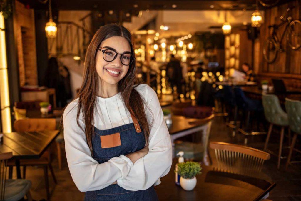 photo of a girl wearing glasses with a restaurant in the background