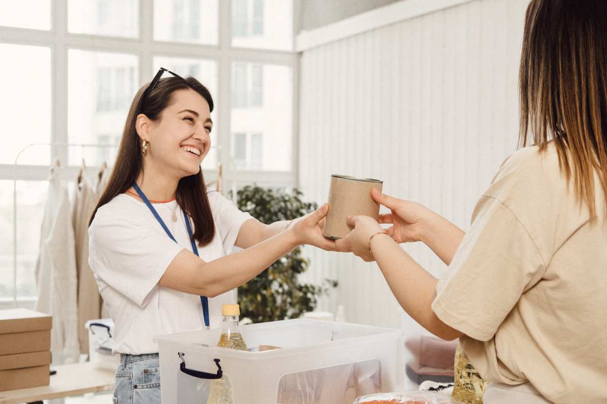 smiling woman handing an object to another woman